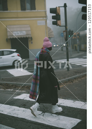 A woman is wearing a pink hat and scarf as she crossed the street 120517153