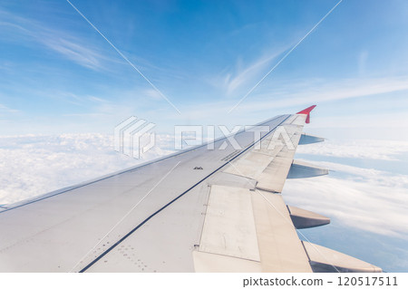 View from the airplane window at a beautiful cloudy sky and the airplane wing View from the airplane window at a beautiful cloudy sky and the airplane wing 120517511