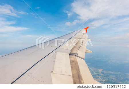 View from the airplane window at a beautiful cloudy sky and the airplane wing View from the airplane window at a beautiful cloudy sky and the airplane wing 120517512
