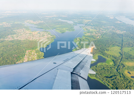 View of airplane wing, blue skies and green land during landing. Airplane window view. 120517513