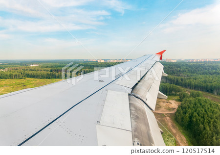 View of airplane wing, blue skies and green land during landing. Airplane window view. View of airplane wing, blue skies and green land during landing. Airplane window view. 120517514