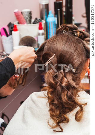Young woman using modern curling iron indoors.Beautiful girl using a curling iron. Hair care concept. Young woman using modern curling iron indoors.Beautiful girl using a curling iron. Hair care concept. 120517573