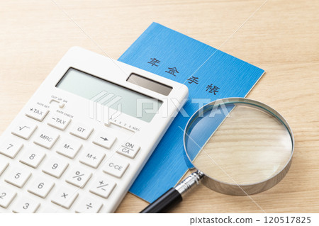 A calculator, pension book and a magnifying glass on a table 120517825