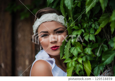 Beautiful tanned girl with natural make-up and wet hair among exotic plants. 120518859