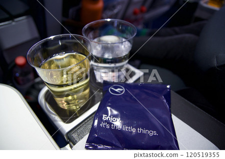FRANKFURT AM MAIN, GERMANY - JUNE 10, 2019: Welcome drink on board a long-haul aircraft with water and sparkling wine and a bag of peanuts 120519355