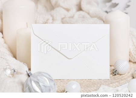 White blank envelope near white sweater, candles and Christmas decor, mockup 120520242