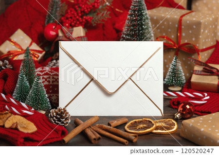 White envelope near Christmas decor, trees, spices and red knitted sweater, winter mockup 120520247