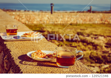 Tea mug and pizza slices on plate, outdoors 120521346