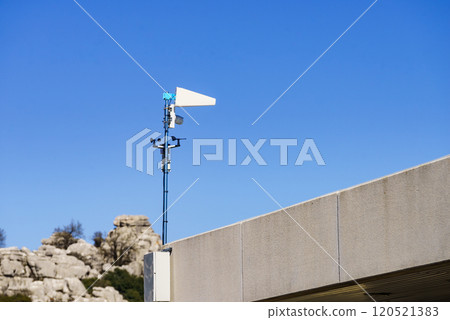 Security video camera and wind indicator against sky. 120521383