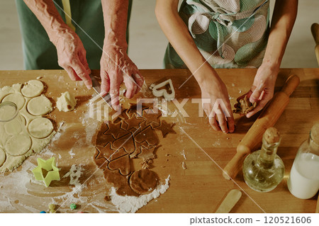 Elderly woman and young child making various shapes of cookies on wooden countertop with scattered flour and baking tools in kitchen setting Elderly woman and young child making various shapes of cookies on wooden countertop with scattered flour and baking tools in kitchen setting 120521606