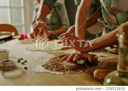 Close-up of family baking cookies together, hands busy with rolling and cutting dough on a kitchen counter, showing teamwork, joy, and love in the process of cooking Close-up of family baking cookies together, hands busy with rolling and cutting dough on a kitchen counter, showing teamwork, joy, and love in the process of cooking 120521610