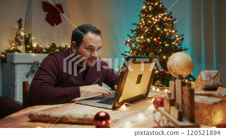 Seated Man Searches Online For Christmas Gifts In His Computer On The Table 120521894