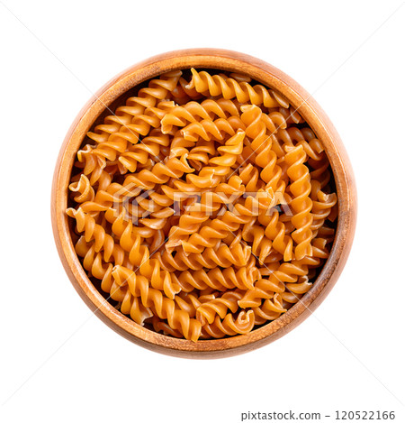 Chickpea spiral pasta, gluten free noodles in a wooden bowl, isolated from above. Small fusilli, a pasta variety with helical or corkscrew shape, made of chickpea flour, an alternative to wheat flour. 120522166