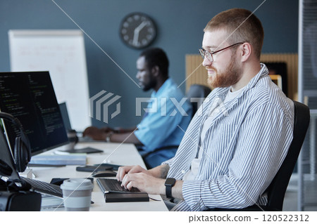 Team of software developers working on computers in modern office with focus on their tasks and coding screens visible on desks Team of software developers working on computers in modern office with focus on their tasks and coding screens visible on desks 120522312
