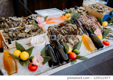 Fresh seafood assortment on ice with oysters, shrimp, and drinks at a gourmet food market display Fresh seafood assortment on ice with oysters, shrimp, and drinks at a gourmet food market display 120522977