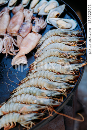 Fresh seafood selection on the grill, including squid, shrimp, mussels, and fish, ready for cooking Fresh seafood selection on the grill, including squid, shrimp, mussels, and fish, ready for cooking 120522991