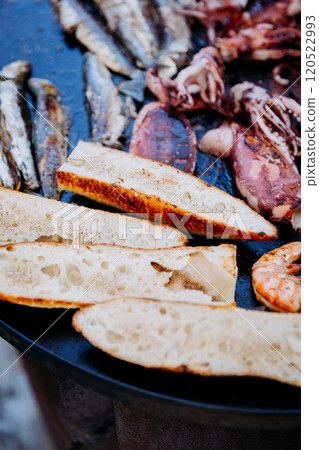 Grilled bread and seafood sizzling on a hot plate, perfect for a delicious Mediterranean feast 120522993