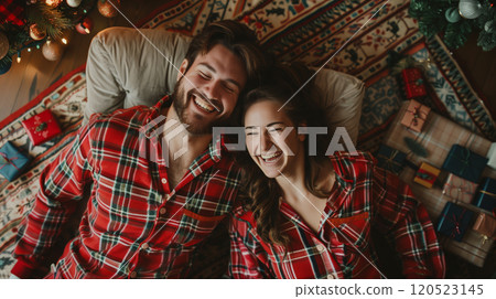 Laughing Couple On Their Backs Wearing Matching Holiday Pajamas Surrounded By Christmas Gifts. Generative AI. 120523145