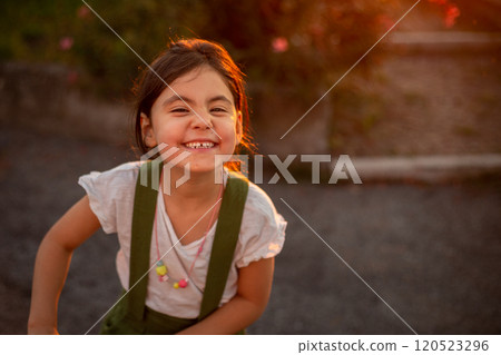 close-up portrait of smiling girl standing in the park looking at camera 120523296
