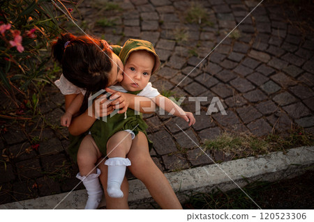upper view of of two sitting children, bigger one holding smaller one in hands 120523306