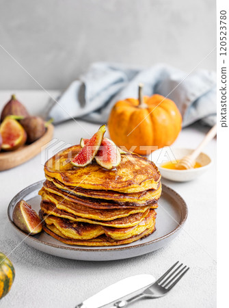 Stack of pumpkin and pancakes with honey and figs on a light background with fresh fruits. 120523780