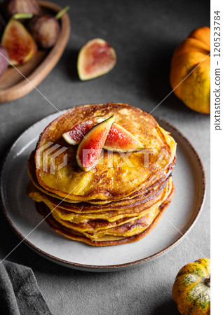 Stack of pumpkin and pancakes with honey and figs on a dark background with fresh fruits 120523784