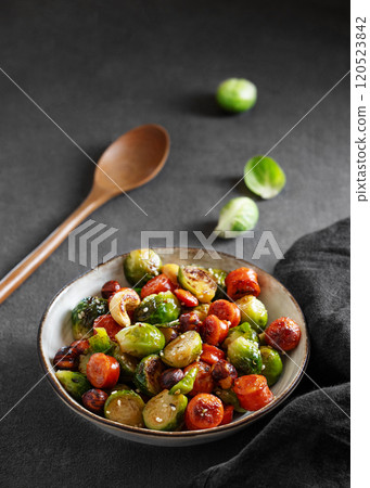 Fried brussels sprouts with nuts in soy sauce on a dark background.  120523842
