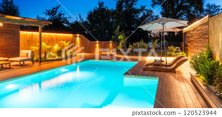 Modern pool with illuminated seating area at night. Concept of luxurious evening relaxation and outdoor ambiance Modern pool with illuminated seating area at night. Concept of luxurious evening relaxation and outdoor ambiance 120523944