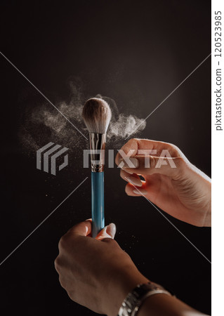 Makeup brush in action with powder particles floating in dramatic lighting, beauty in motion Makeup brush in action with powder particles floating in dramatic lighting, beauty in motion 120523985