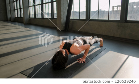 Pilates workout. Yoga training. Athletic woman in activewear practicing plank exercise on sport mat in gym fitness studio indoors. Pilates workout. Yoga training. Athletic woman in activewear practicing plank exercise on sport mat in gym fitness studio indoors. 120529240
