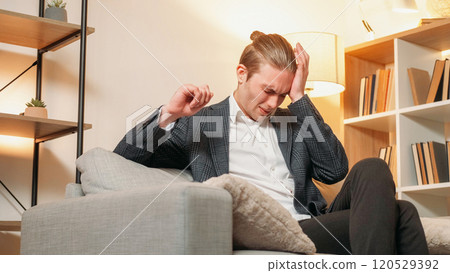 Headache pain. Health story. Business man suffering migraine on sofa in modern suit with lighted lamp in modern interior. 120529392