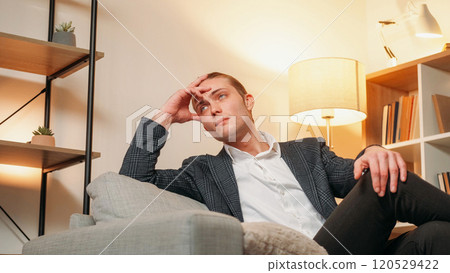 Business thought. Future plan. Pensive man sitting on sofa in modern suit dreaming of future success new goals. Business thought. Future plan. Pensive man sitting on sofa in modern suit dreaming of future success new goals. 120529422