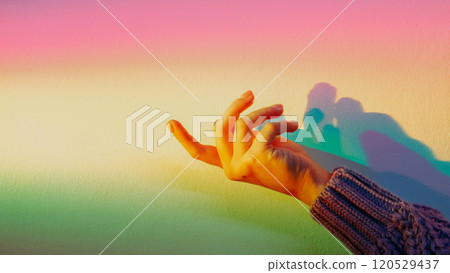 Spiritual energy hand. Advertising background. Rainbow pastel. Female fingers on blur glowing color gradient light wall with copy space. Spiritual energy hand. Advertising background. Rainbow pastel. Female fingers on blur glowing color gradient light wall with copy space. 120529437