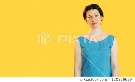 Sad disappointed woman in blue looking sad expressing melancholy isolated on yellow empty space background. Sad disappointed woman in blue looking sad expressing melancholy isolated on yellow empty space background. 120529659
