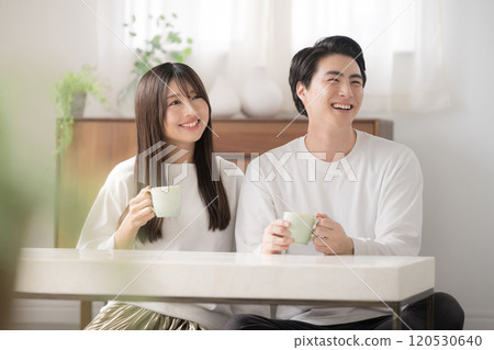 Couple relaxing in a room looking out the window with drinks Couple relaxing in a room looking out the window with drinks 120530640