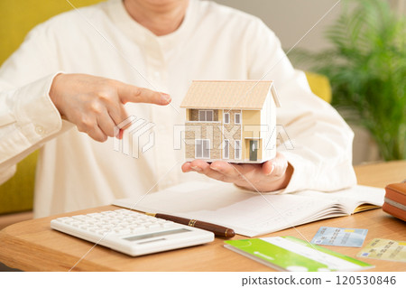 A middle-aged woman managing her household finances and a model house 120530846