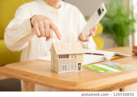 A middle-aged woman managing her household finances and a model house 120530850