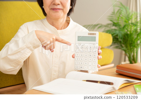 一位中年婦女微笑著指著計算機和家庭帳本 一位中年婦女微笑著指著計算機和家庭帳本 120533209