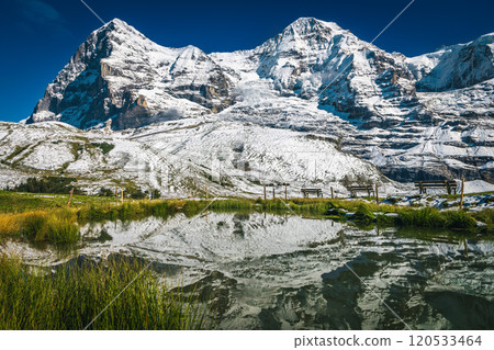 Small lake and high snowy mountains in background, Grindelwald, Switzerland 120533464