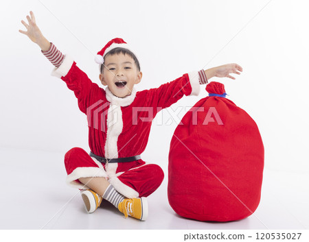 Little Kid Dressed as Santa sitting with  Bag Full of Gifts 120535027