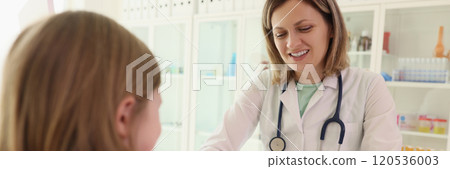 Girl smears artificial jaw model with toothpaste with doctor Girl smears artificial jaw model with toothpaste with doctor 120536003