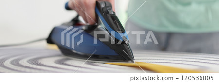 Male person irons yellow tie with hot steam in morning Male person irons yellow tie with hot steam in morning 120536005