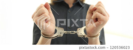Female person with handcuffs on wrists in prison cell 120536023