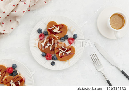 A heap of heart shaped pancakes with berries and a fork on the white plate on grey background A heap of heart shaped pancakes with berries and a fork on the white plate on grey background 120536180