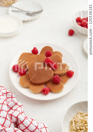 A heap of heart shaped pancakes on the white plate with raspberries on the white background A heap of heart shaped pancakes on the white plate with raspberries on the white background 120536181