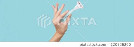 Precision in hand: A razor held against a striking blue backdrop, capturing the essence of grooming finesse Precision in hand: A razor held against a striking blue backdrop, capturing the essence of grooming finesse 120536200