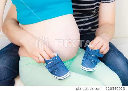 Couple expecting baby, man playing with little shoes 120540023