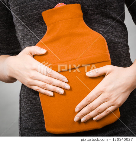 Girl having stomach ache, holding hot water bottle Girl having stomach ache, holding hot water bottle 120540027