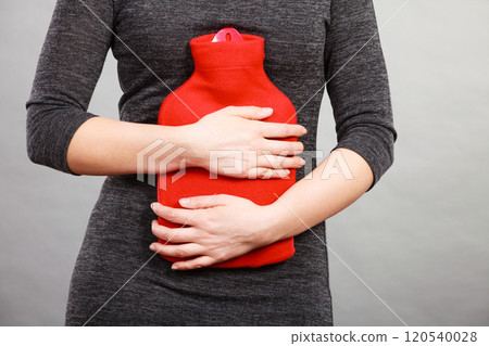 Girl having stomach ache, holding hot water bottle Girl having stomach ache, holding hot water bottle 120540028