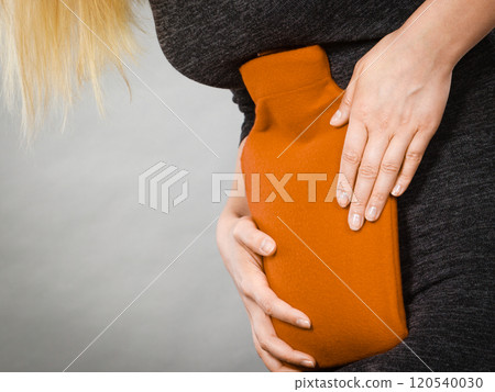 Girl having stomach ache, holding hot water bottle Girl having stomach ache, holding hot water bottle 120540030